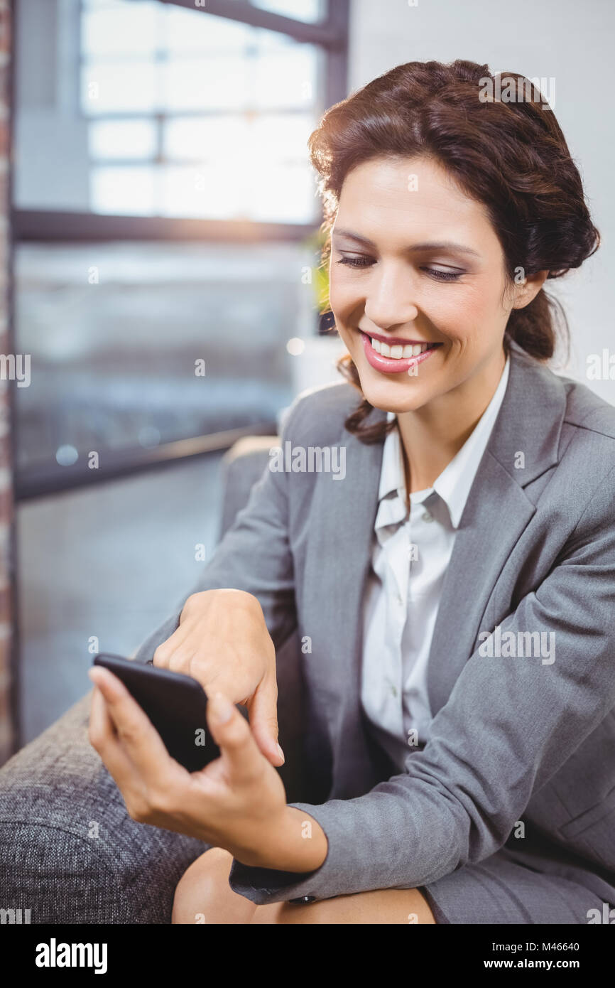 Businesswoman smiling while looking at mobile phone Banque D'Images