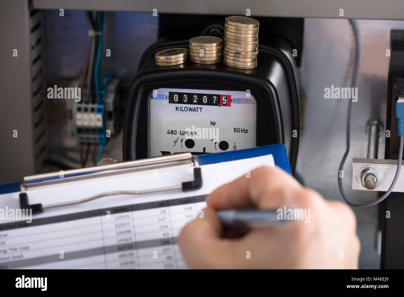Close-up d'un technicien part écrit Lecture de compteur avec coin empilés sur le Presse-papiers Banque D'Images