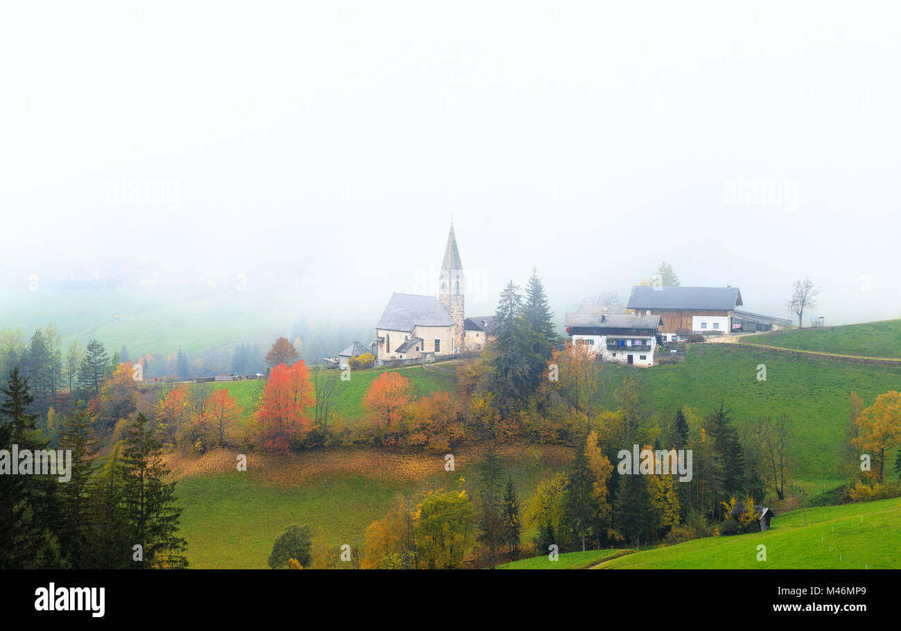 Église de Santa Magdalena dans le brouillard d'automne. Funes Valley, South Tyrol, Dolomites, Italie Banque D'Images