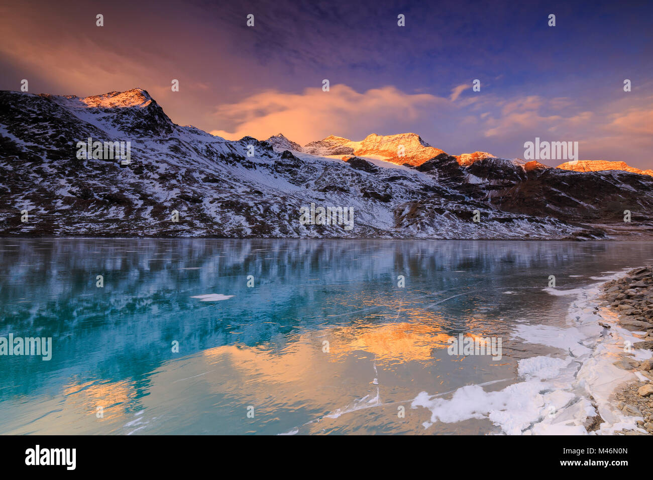 Superbe lever de soleil sur le lac gelé Bianco(Lac Blanc), Col de la Bernina, Engadine, Grisons, Suisse. Banque D'Images