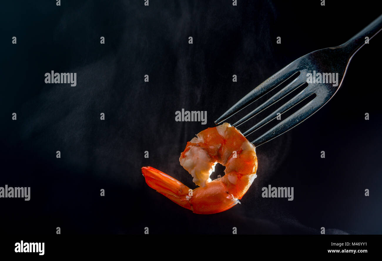 Crevettes cuites à la vapeur sur fourche isolé sur fond sombre avec copie espace. Buffet de fruits de mer dans le concept. Utilisation pour buffet de fruits de mer promotions advertisin Banque D'Images