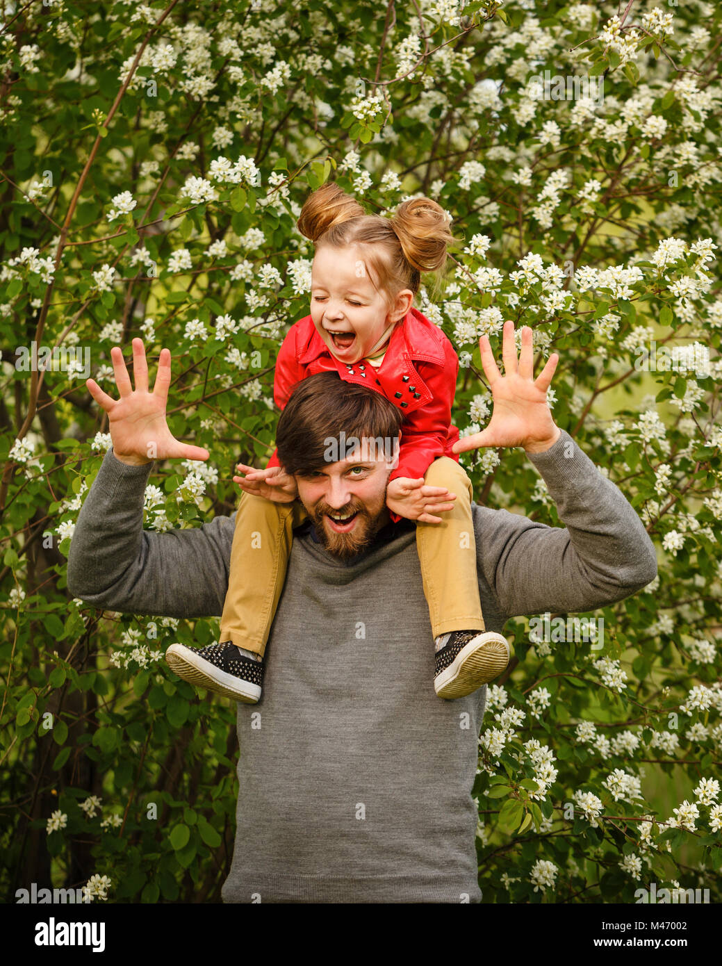 Le temps passé en famille. Le père détient sur ses épaules une petite fille  dans un manteau de cuir. S'y greffent. Ils rient et niaises. Marche de  printemps Photo Stock - Alamy