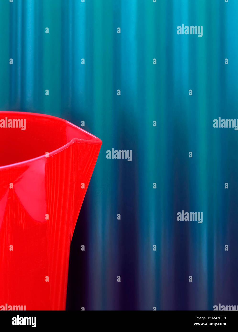 Bécher en plastique rouge sur fond texturé bleu Banque D'Images