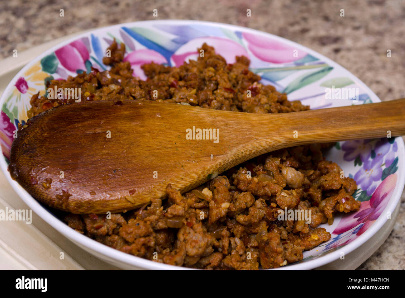 Bol de saucisse italienne chaude hachée avec cuillère en bois Banque D'Images