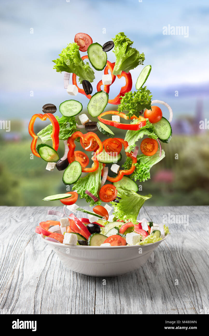 Mélange de légumes frais tomber dans un bol de salade Banque D'Images