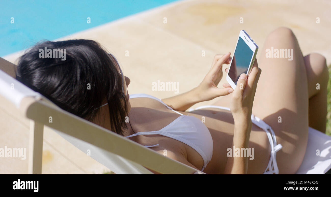 Jeune femme à la navigation sur le mobile dans le soleil de l'été Banque D'Images