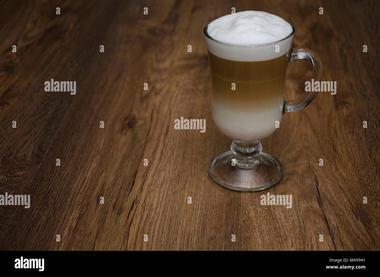 Boisson chaude avec du café et du lait, latte, cappuccino, dans un beau verre en verre, sur une table en bois Banque D'Images