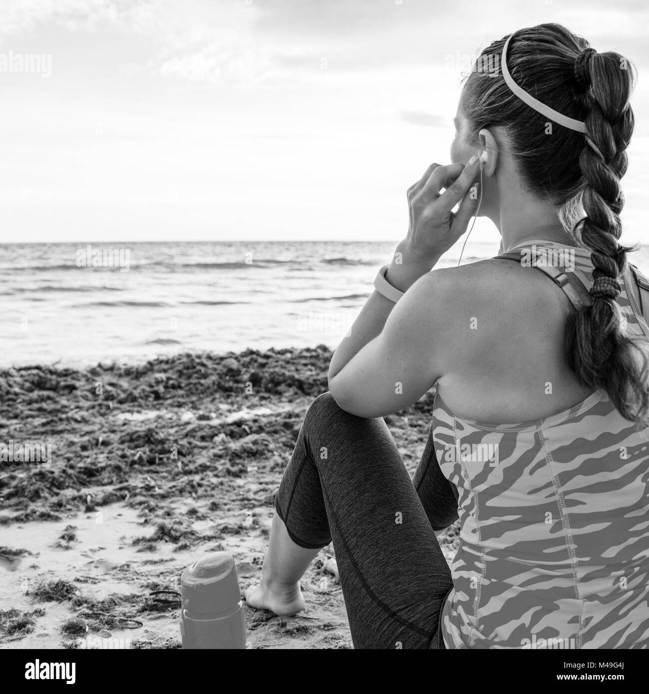 Côté mer sauvage rafraîchissante d'entraînement. Vus de derrière, grande sportive dans les équipements sportifs sur le littoral avec des écouteurs à écouter la musique Banque D'Images