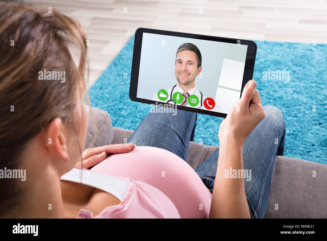 Jeune femme enceinte la visioconférence avec médecin homme sur Digital Tablet Banque D'Images