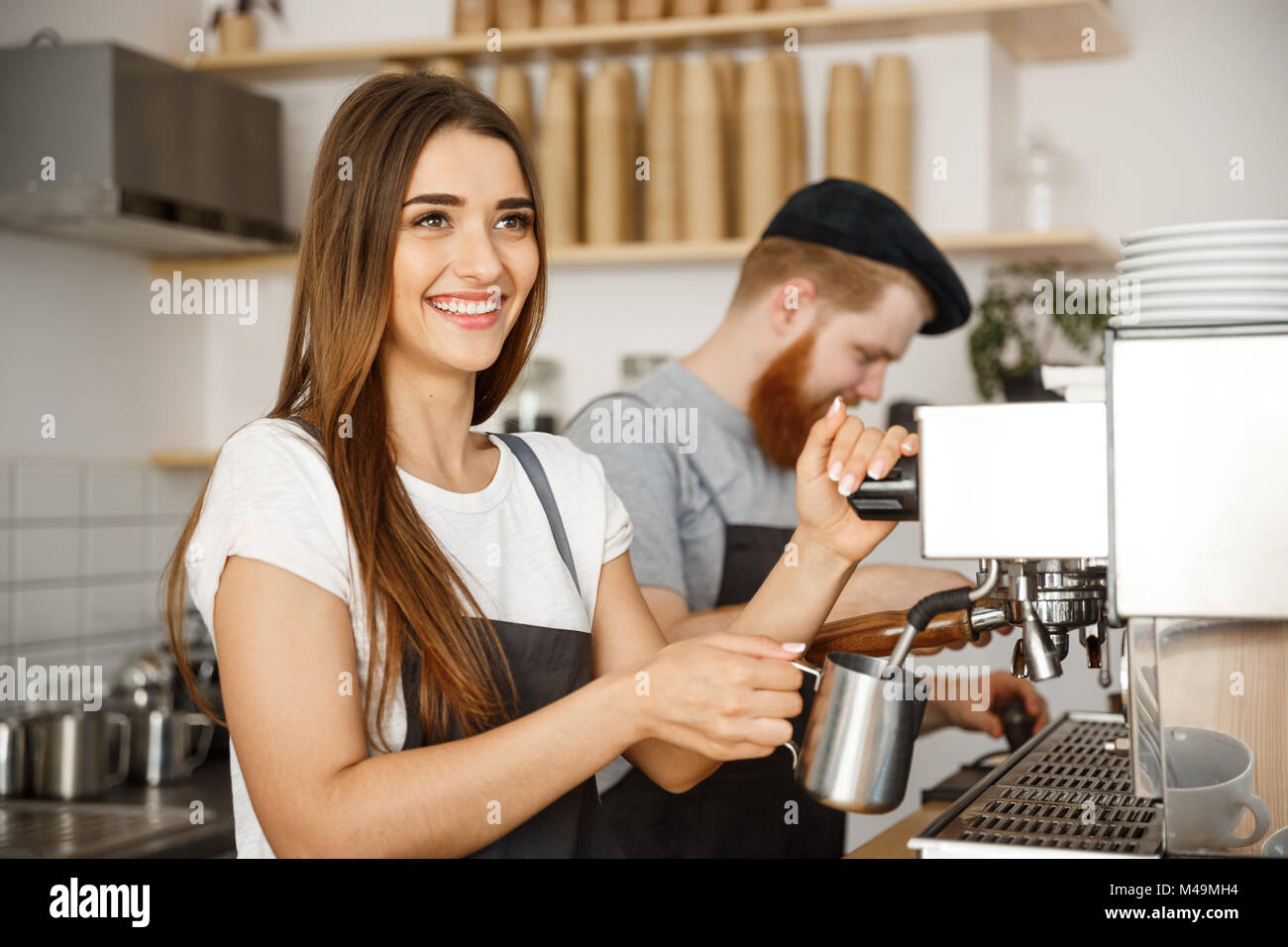 Concept d'entreprise Café - portrait de dame dans la préparation et le tablier barista lait vapeur pour le café avec son partenaire tout en se tenant au café. Banque D'Images