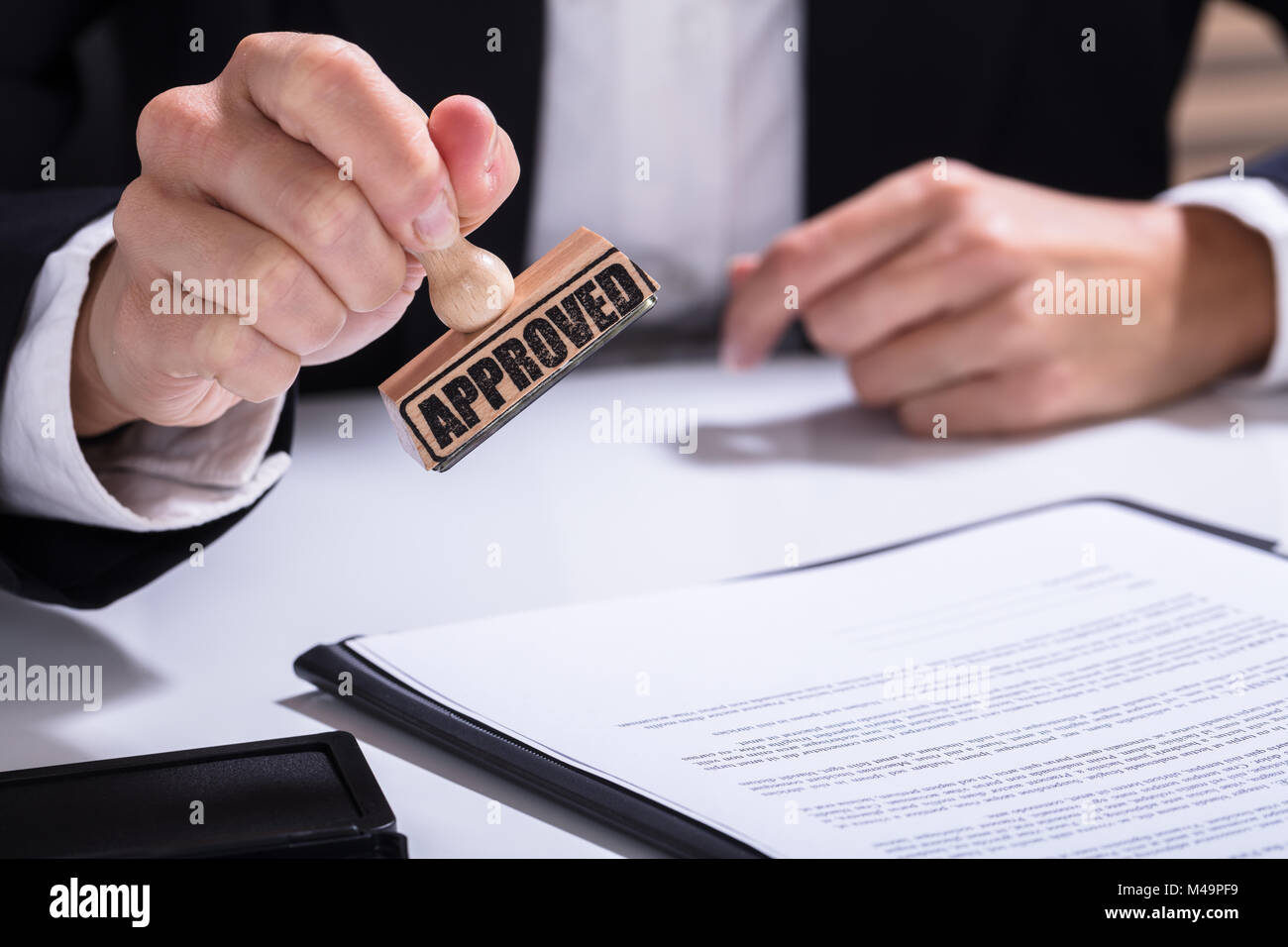 Close-up de personne à l'aide de mains stamper sur le document avec le texte approuvé Banque D'Images