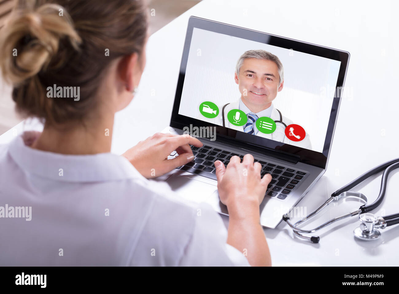 Vue arrière d'une femme chat vidéo avec un médecin homme On Laptop Banque D'Images