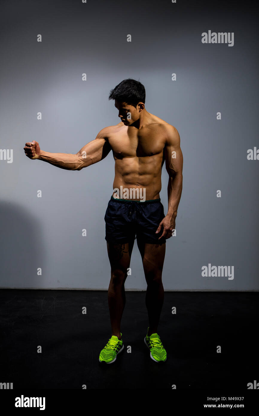 Un modèle de remise en forme fléchit ses biceps à la recherche vers le  muscle. Long Shot Photo Stock - Alamy