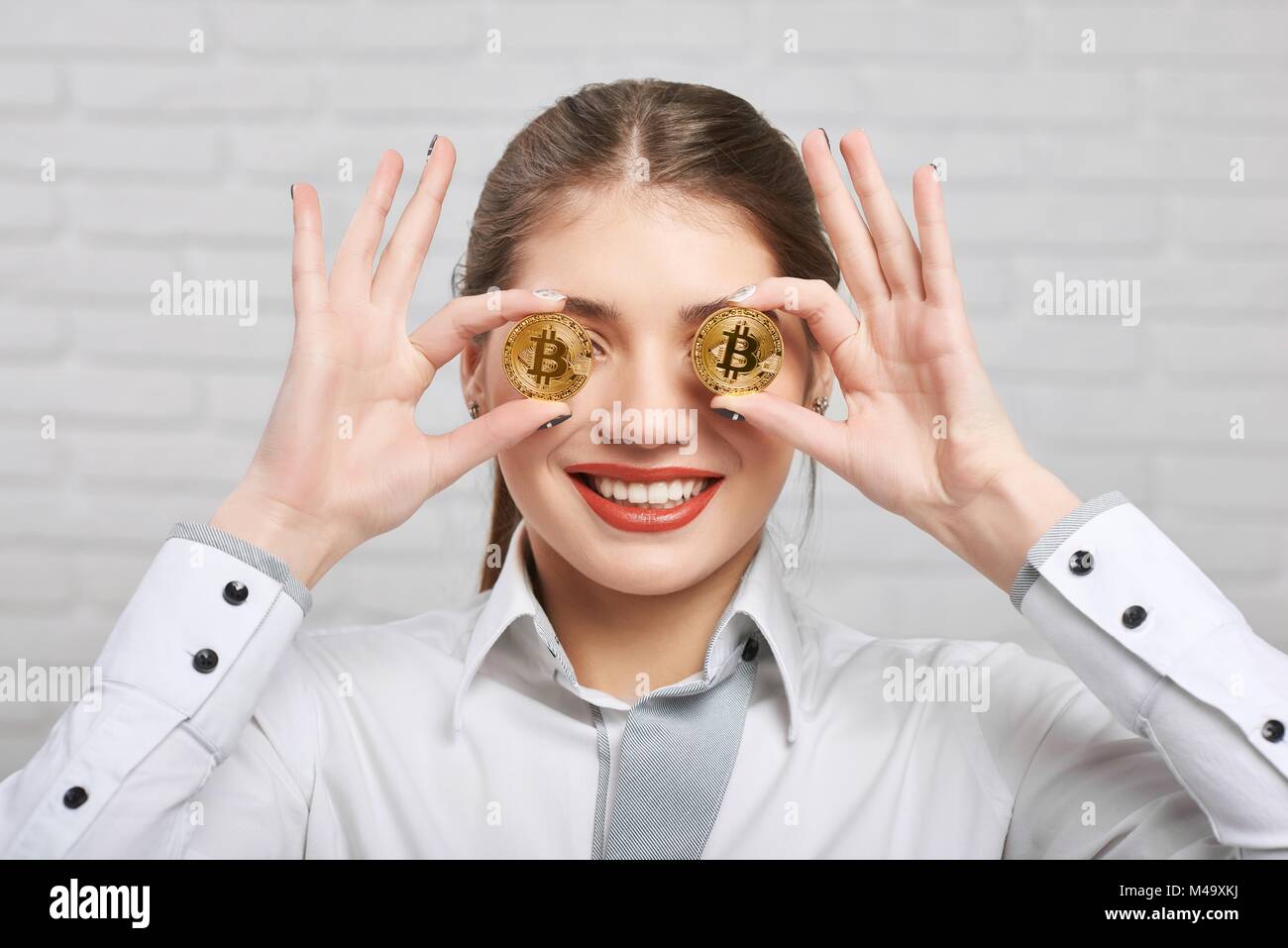 Smiling girl détient deux golden bitcoins sur le fond blanc. Banque D'Images