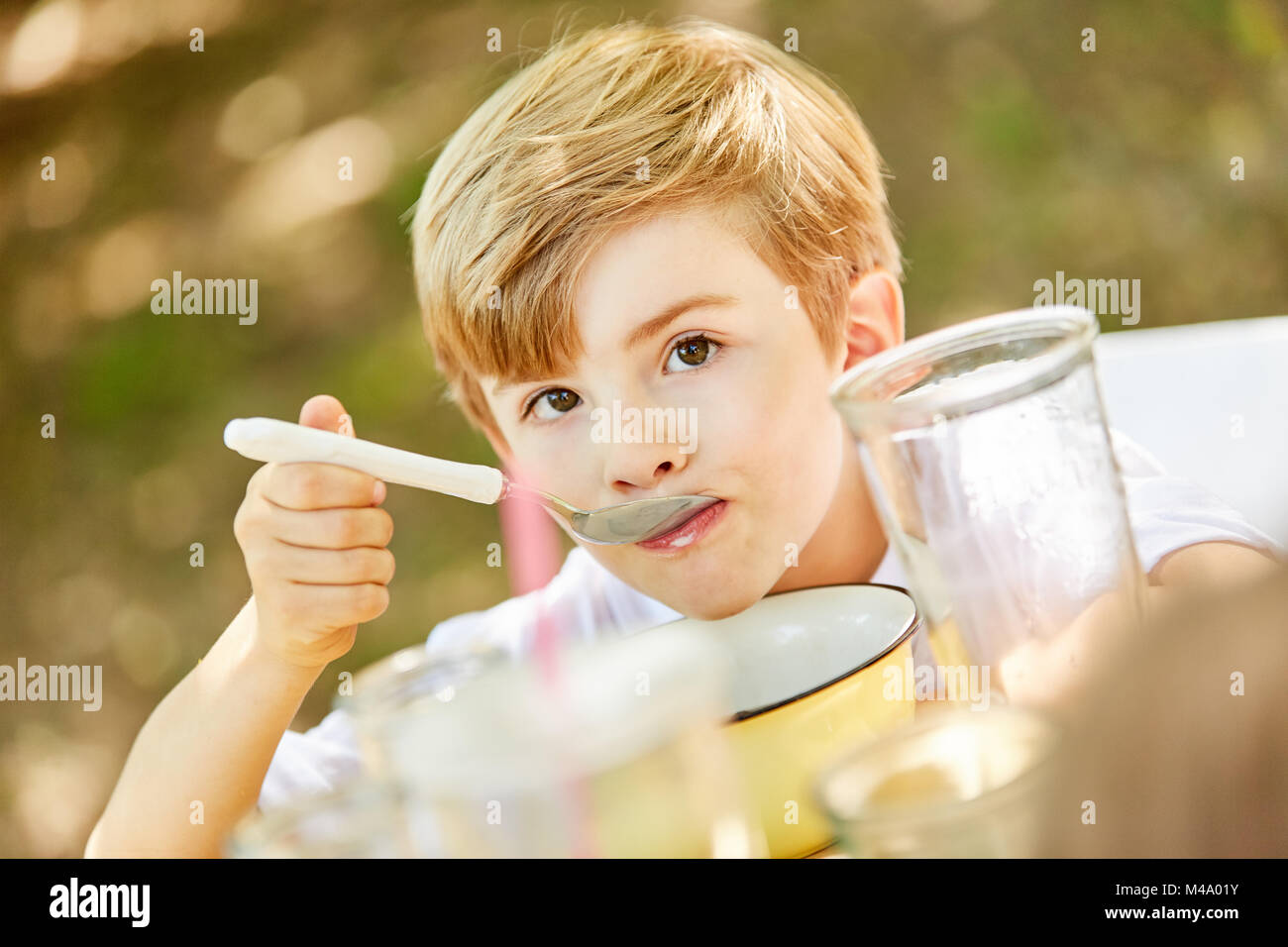 Boy est bien manger le matin des céréales pour le petit-déjeuner dans le jardin ou à la maison Banque D'Images