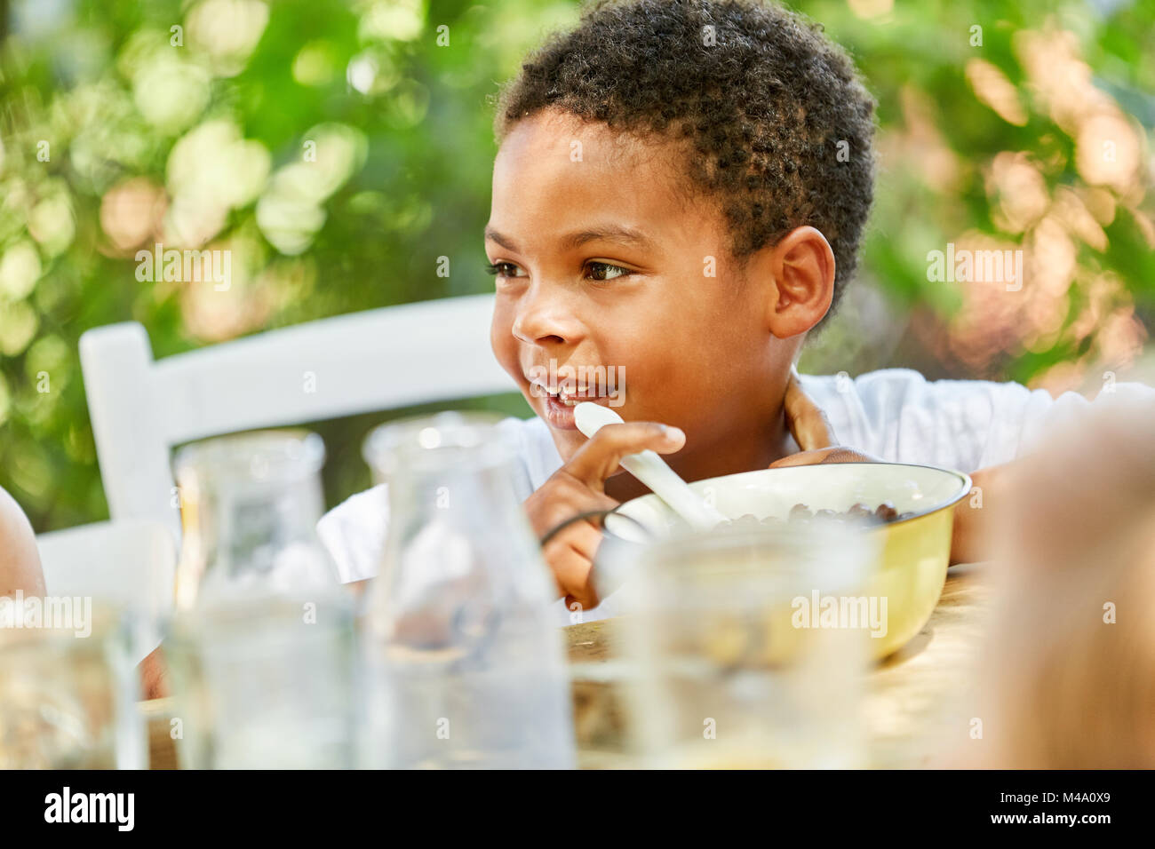 Petit garçon africain est manger des céréales pour le petit-déjeuner dans le jardin d'enfants Banque D'Images