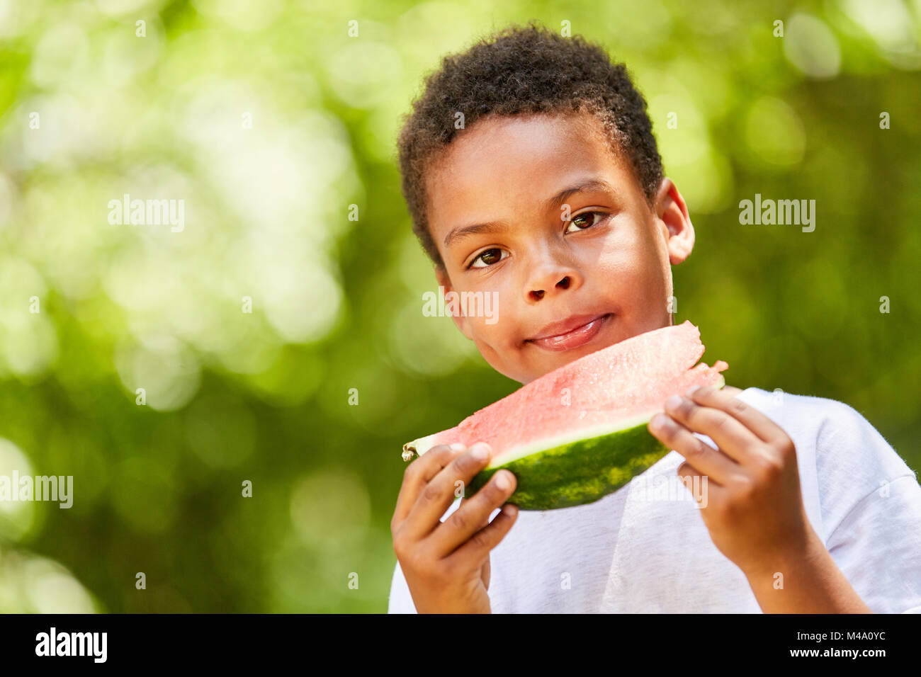 African boy mange une pastèque juteuse comme un régime alimentaire sain Banque D'Images