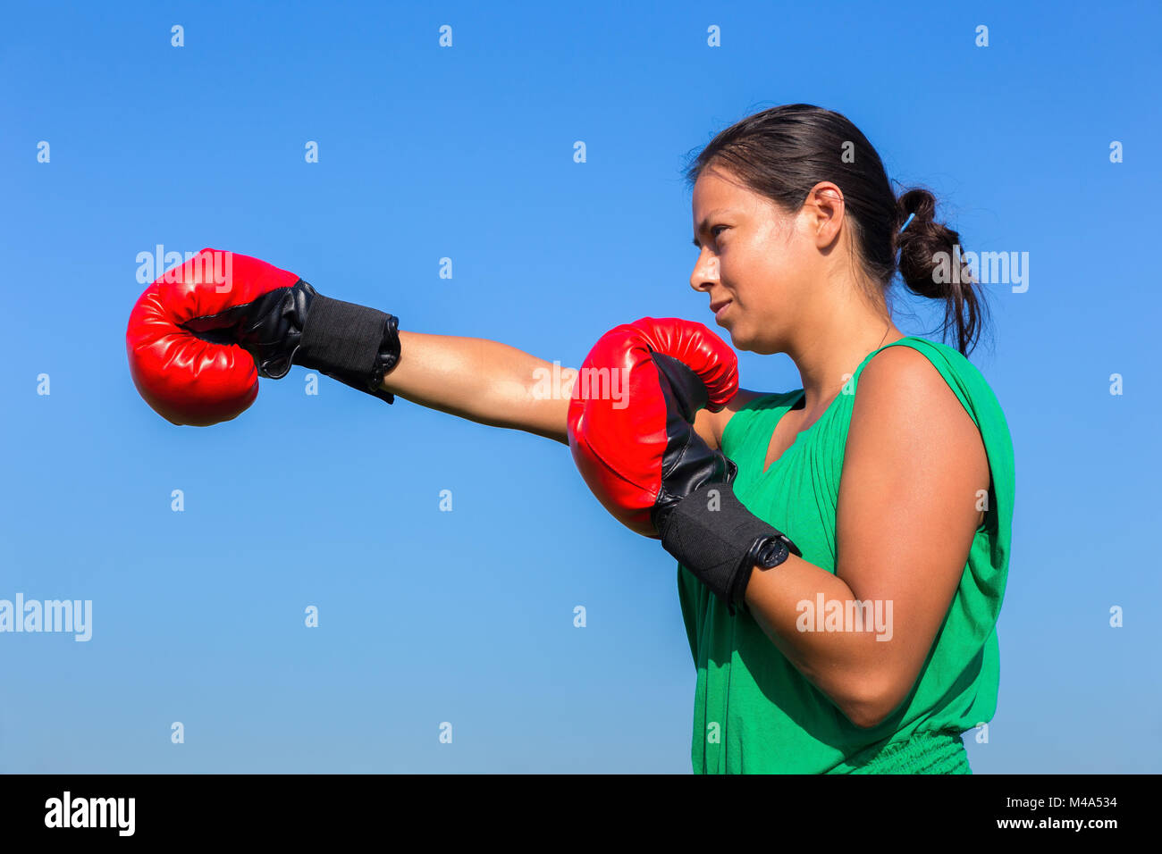 Jeune femme portant des gants de boxe rouge avec ciel bleu Banque D'Images