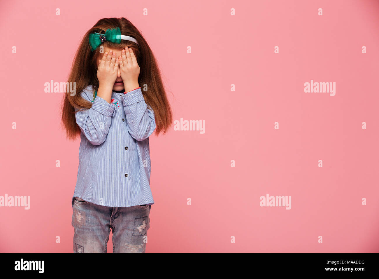 Studio photo de lycéenne 5-6 ans couvrant les yeux avec les mains, de pleurer ou d'être effrayé plus isolé sur fond rose Banque D'Images