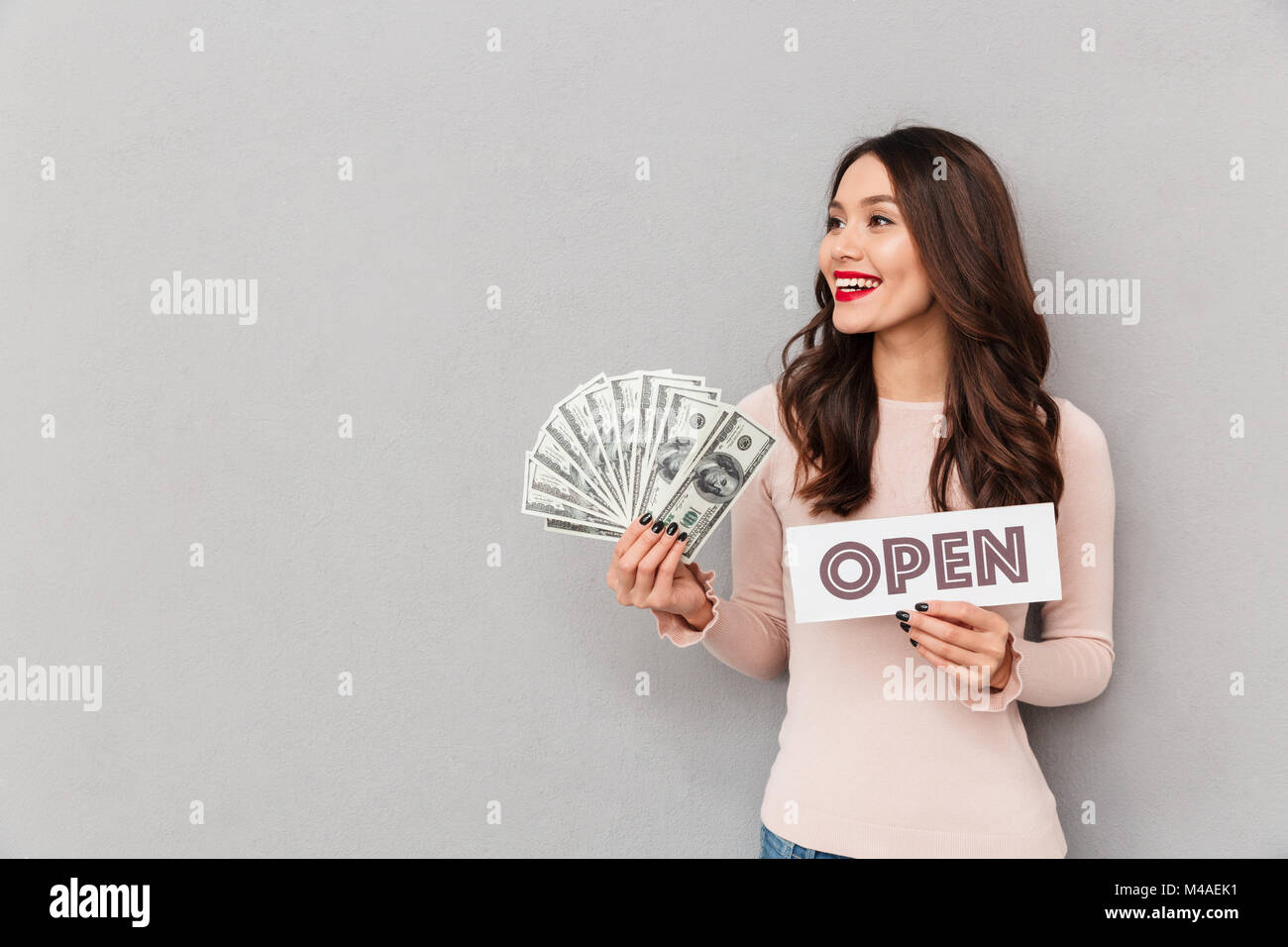 Demi-tour droit de lucky woman holding open sign et ventilateur d'argent, plus de billets isolés sur fond gris Banque D'Images