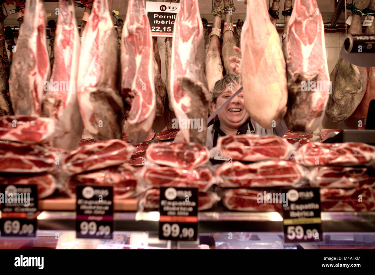 Une femme heureuse est la vente de la spécialité espagnol jambon séché au marché local à Barcelone. L'Espagne 2011. Banque D'Images