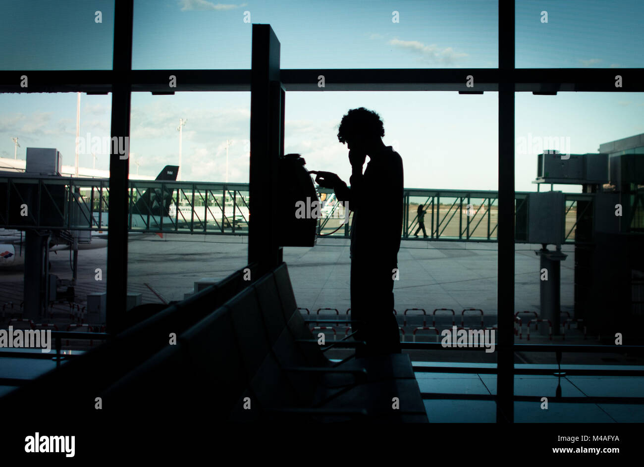 Un passager est en train de tuer le temps d'attente dans un aéroport en appelant accueil à partir d'un téléphone public. 2011. Banque D'Images