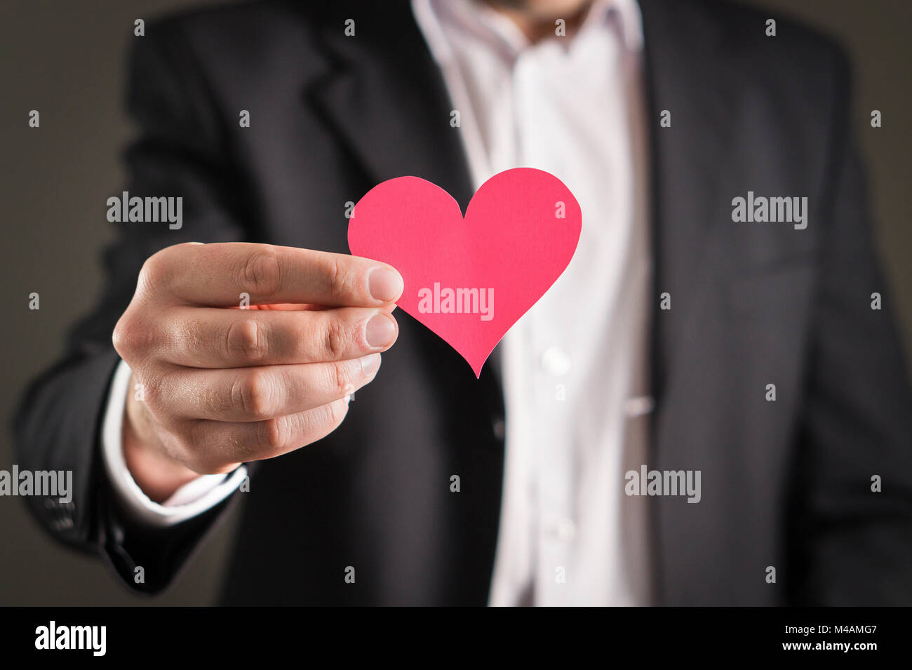 Homme en costume et un carton de papier. Homme d'affaires ou fiancé avec un symbole d'amour. Proposition de mariage, ou de rencontres, valentine's day concept. Banque D'Images