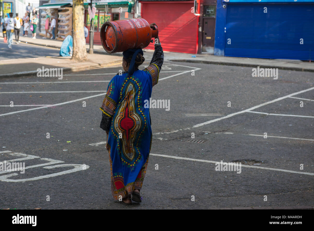 Londres, Royaume-Uni. Femme porte sur la tête l'équilibre entre une bouteille de gaz. Notting Hill Carnival. Banque D'Images