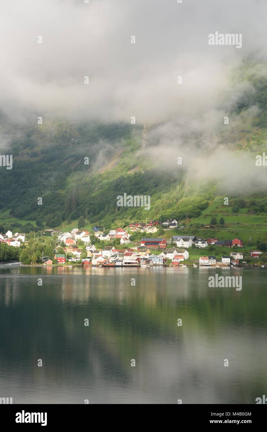 Village norvégien à la base de la montagne par fjord Banque D'Images