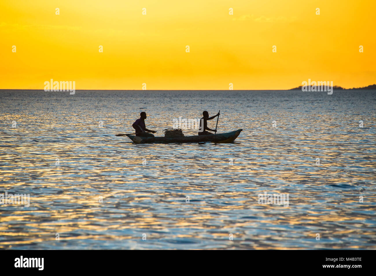Les pêcheurs d'un rétro-éclairage dans un petit bateau de pêche au coucher du soleil, le lac Malawi,Cape Maclear,Malawi,Afrique Banque D'Images