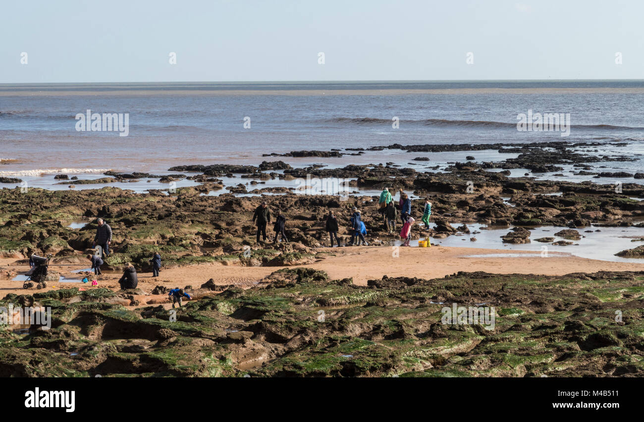 Les gens apprécient rock mise en commun sur la plage de Sidmouth, Devon, dans des conditions météorologiques de février. Banque D'Images