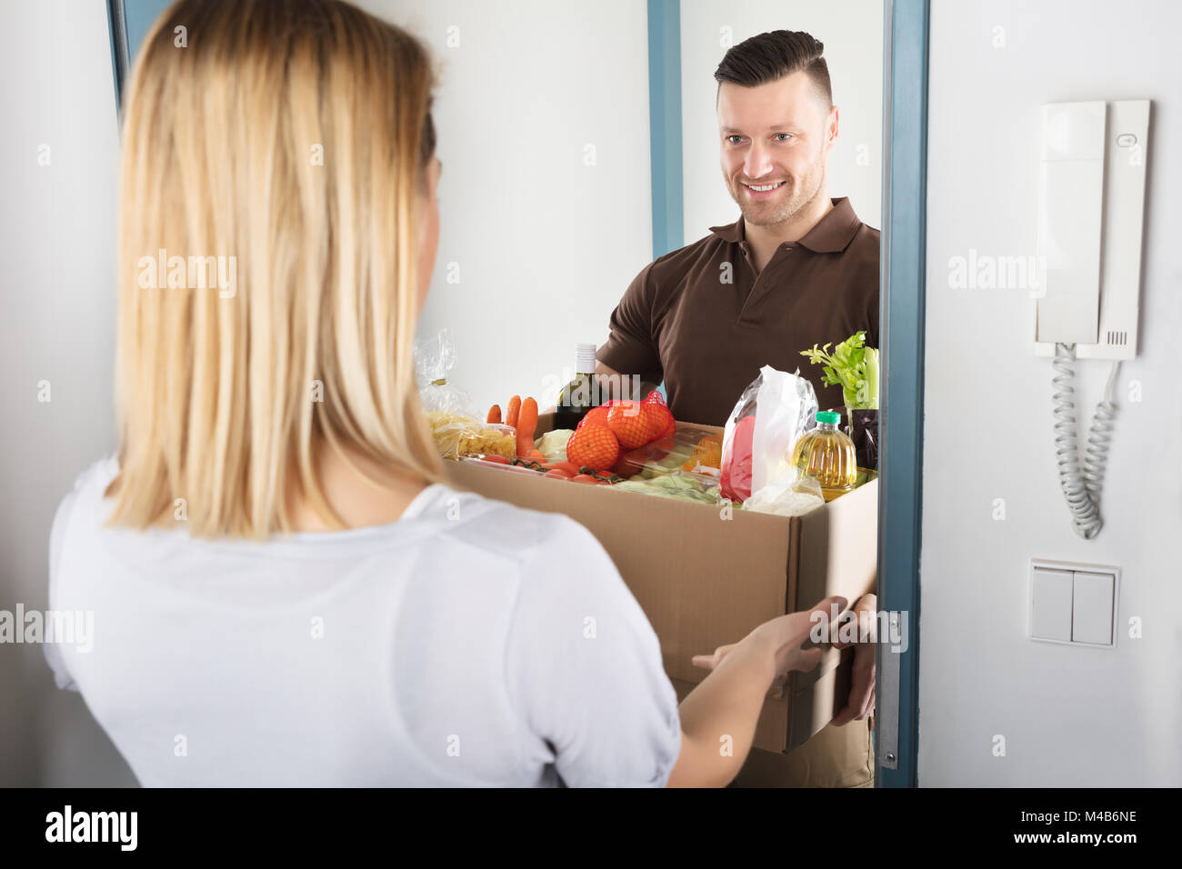 Jeune femme d'accepter plein de carton de livraison d'épicerie à Man Banque D'Images