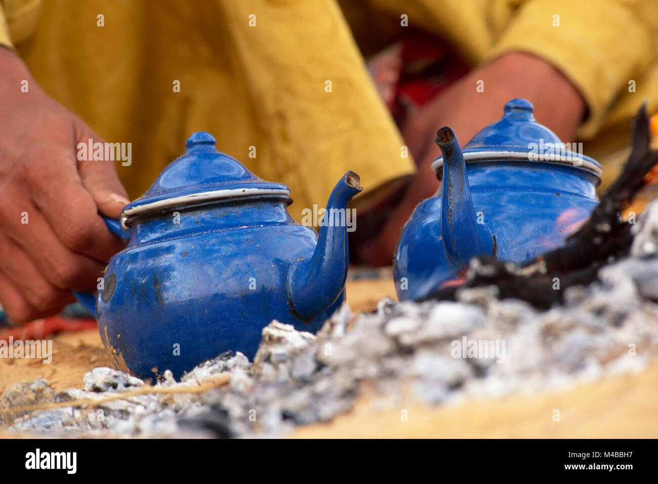L'Algérie. Près de Djanet. Désert du Sahara. L'homme de tribu touareg faire du thé. Au feu. Réchauffement théières Close-up théières. Nomad. Banque D'Images