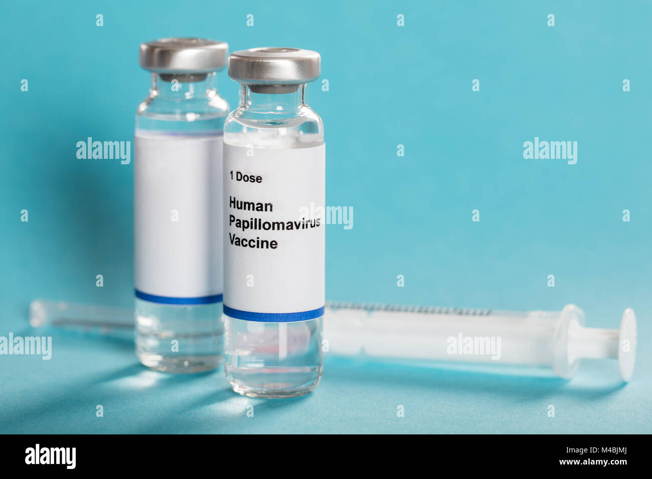 Le vaccin contre le virus du papillome humain dans des bouteilles avec la seringue sur fond bleu turquoise Banque D'Images