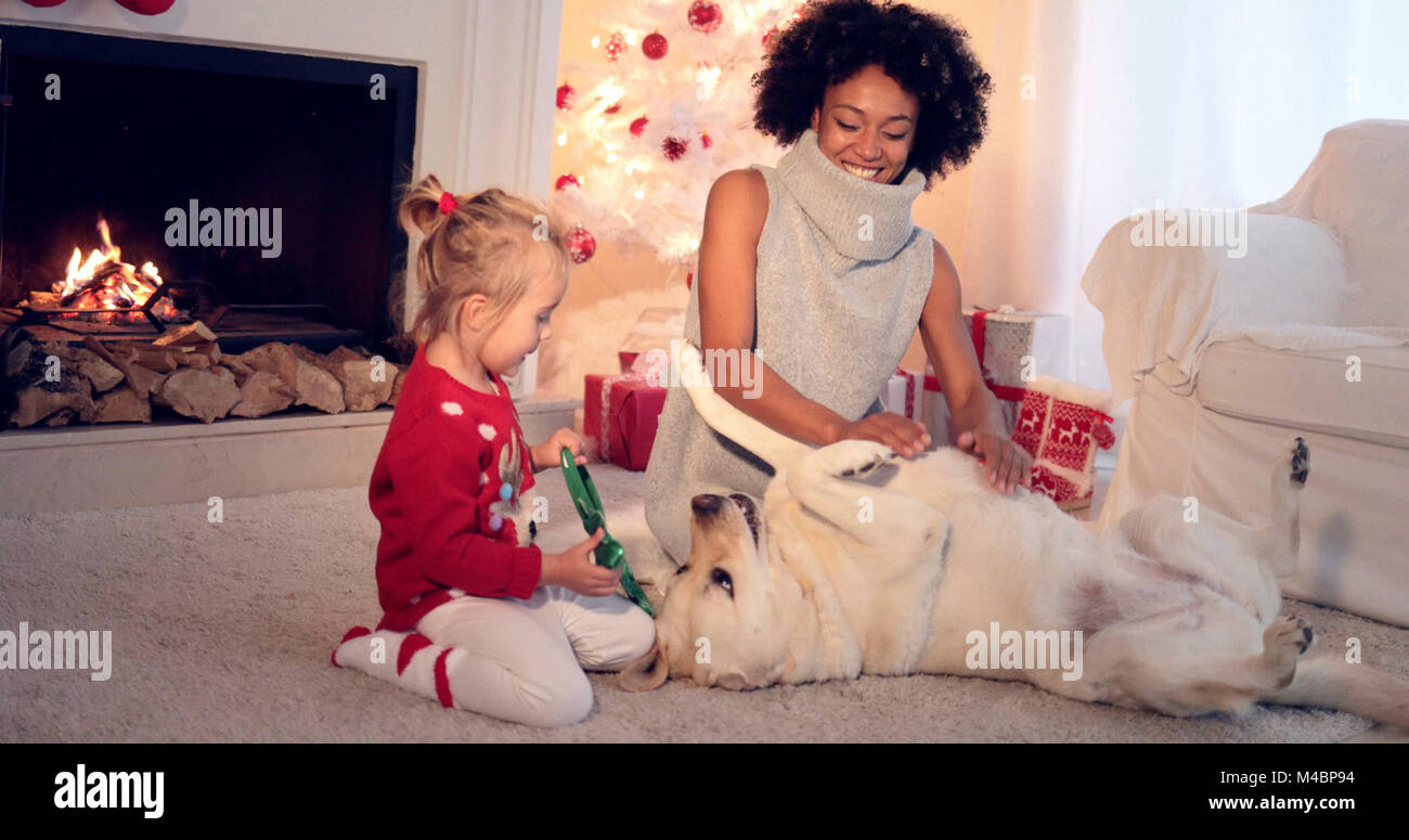 Mère et fille en pulls jouer avec chien Banque D'Images
