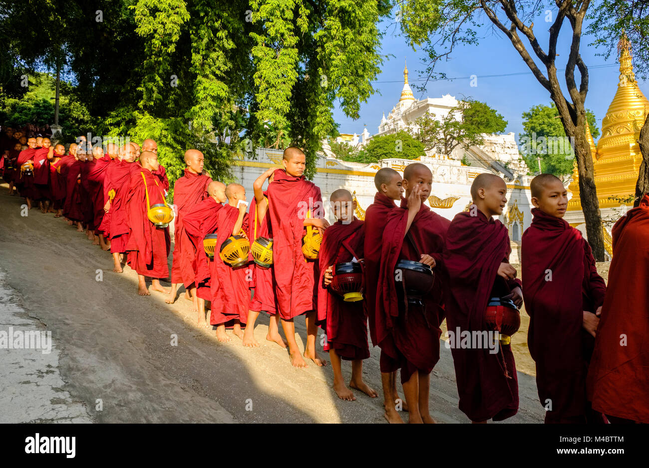 Les moines bouddhistes font la file dans une longue rangée de recevoir des dons dans un monastère Banque D'Images