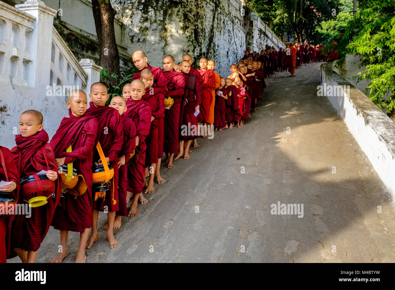 Les moines bouddhistes font la file dans une longue rangée de recevoir des dons dans un monastère Banque D'Images