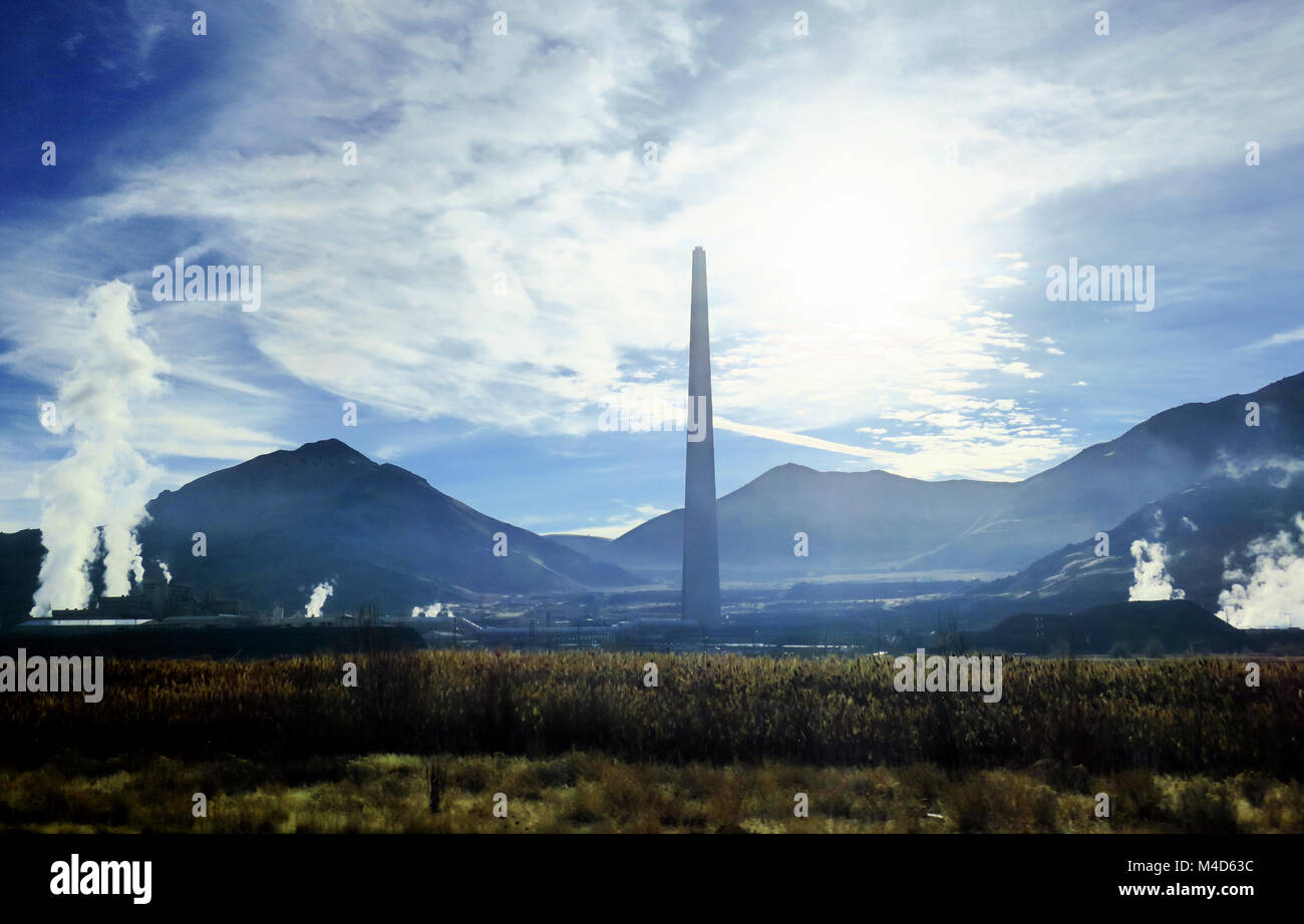 Une cheminée crachant dans l'air vapeur blanche sur un ciel bleu. Banque D'Images