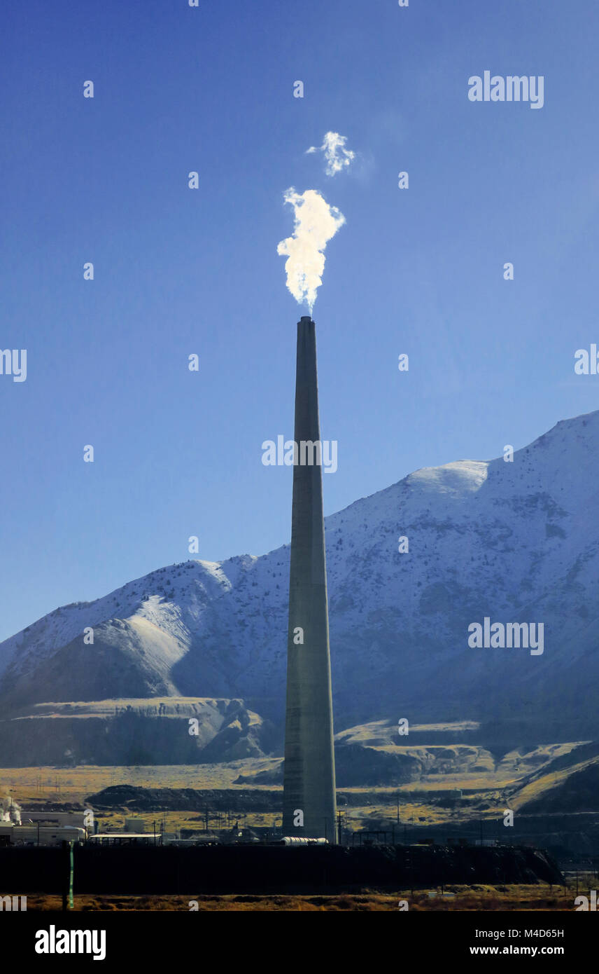 Une cheminée crachant dans l'air vapeur blanche sur un ciel bleu. Banque D'Images