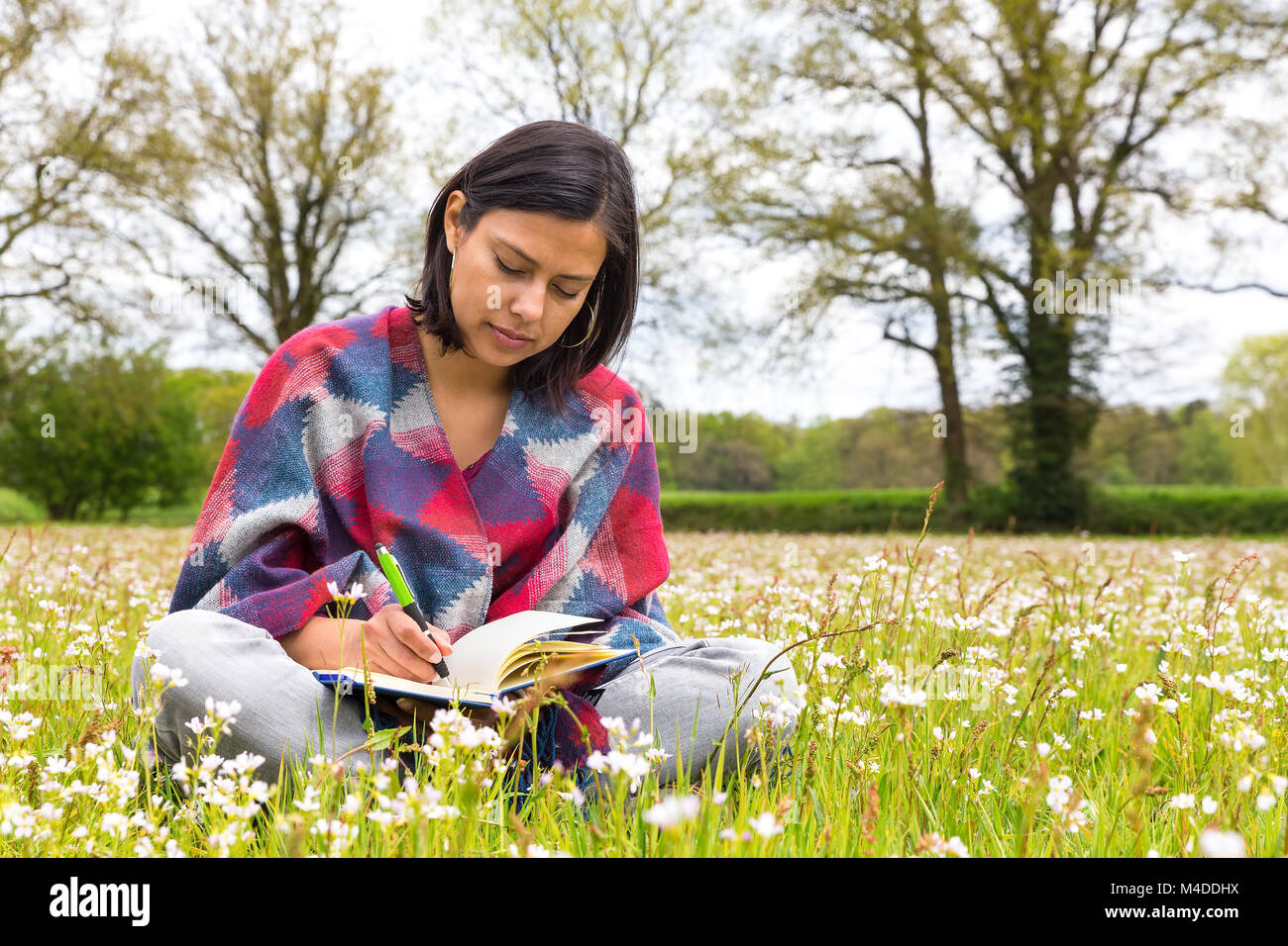 Femme écrivant en prairie avec les fleurs du printemps Banque D'Images