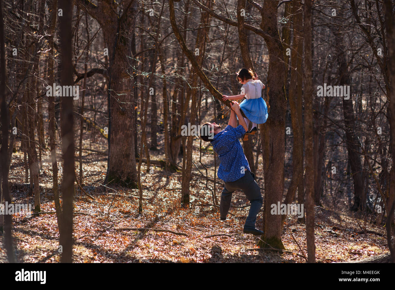 Girl climbing un arbre avec son père Banque D'Images