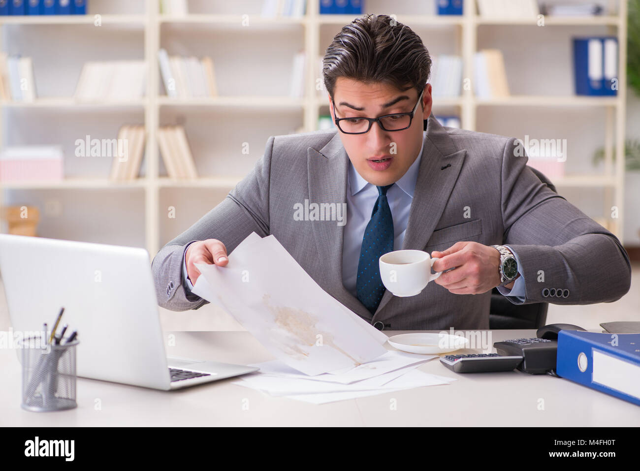 Businessman de renverser du café sur des documents importants Banque D'Images Businessman de renverser du café sur des documents importants Banque D'Images