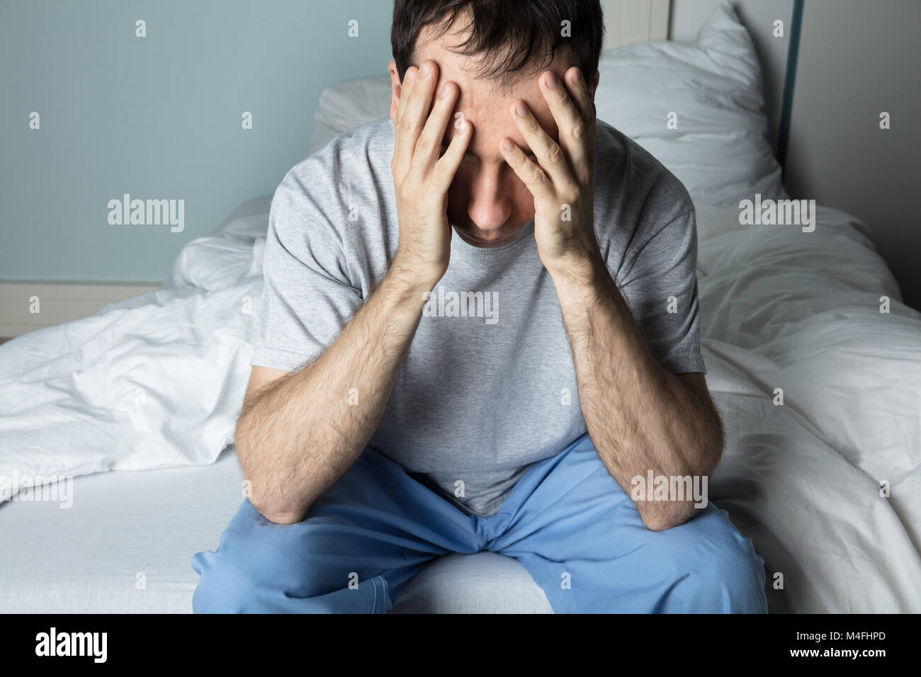 Close-up of a souligné l'homme assis sur le lit à la maison Banque D'Images