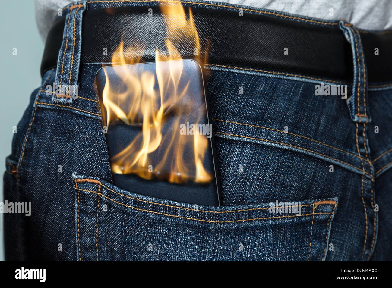 Close-up of A Burning Phone à l'intérieur de la poche arrière de Jeans Banque D'Images