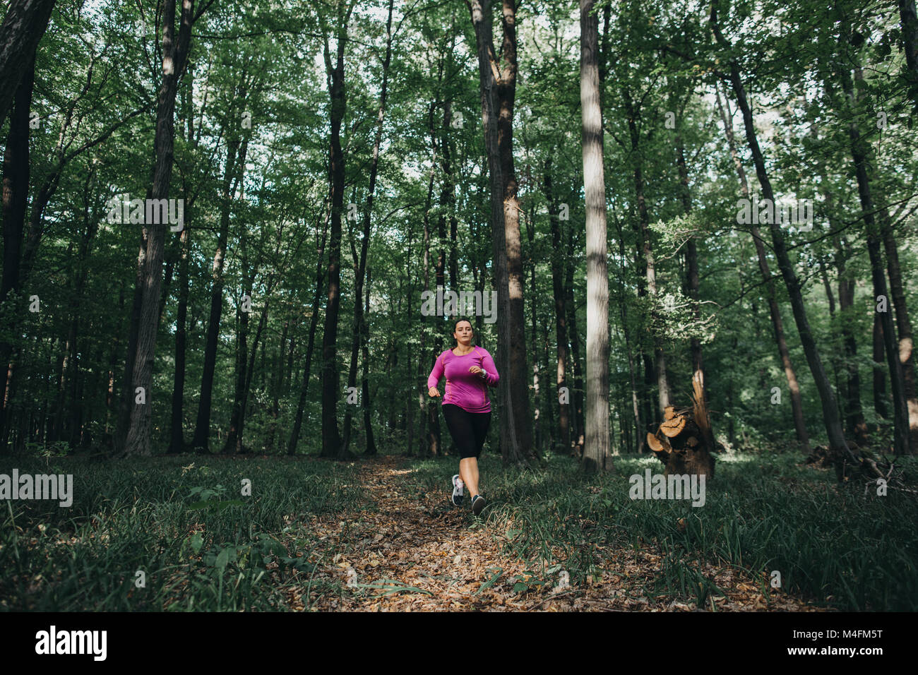 Vue de face d'une coureuse d'essayer de rester en forme et le jogging dans une forêt. Banque D'Images