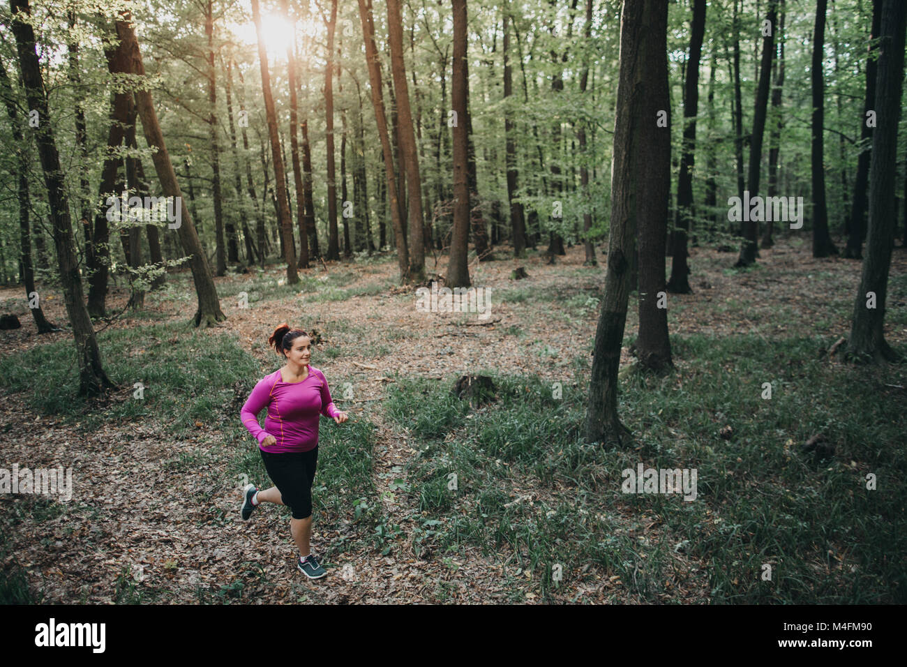 Vue frontale d'une coureuse heureux d'essayer de rester en forme et en marche à travers les bois. Banque D'Images