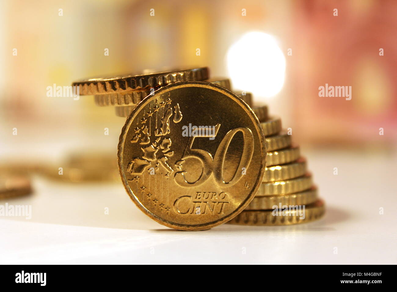 Pièce en Euro, 50 cents, gros plan, empilés sur un bureau blanc avec billets derrière Banque D'Images