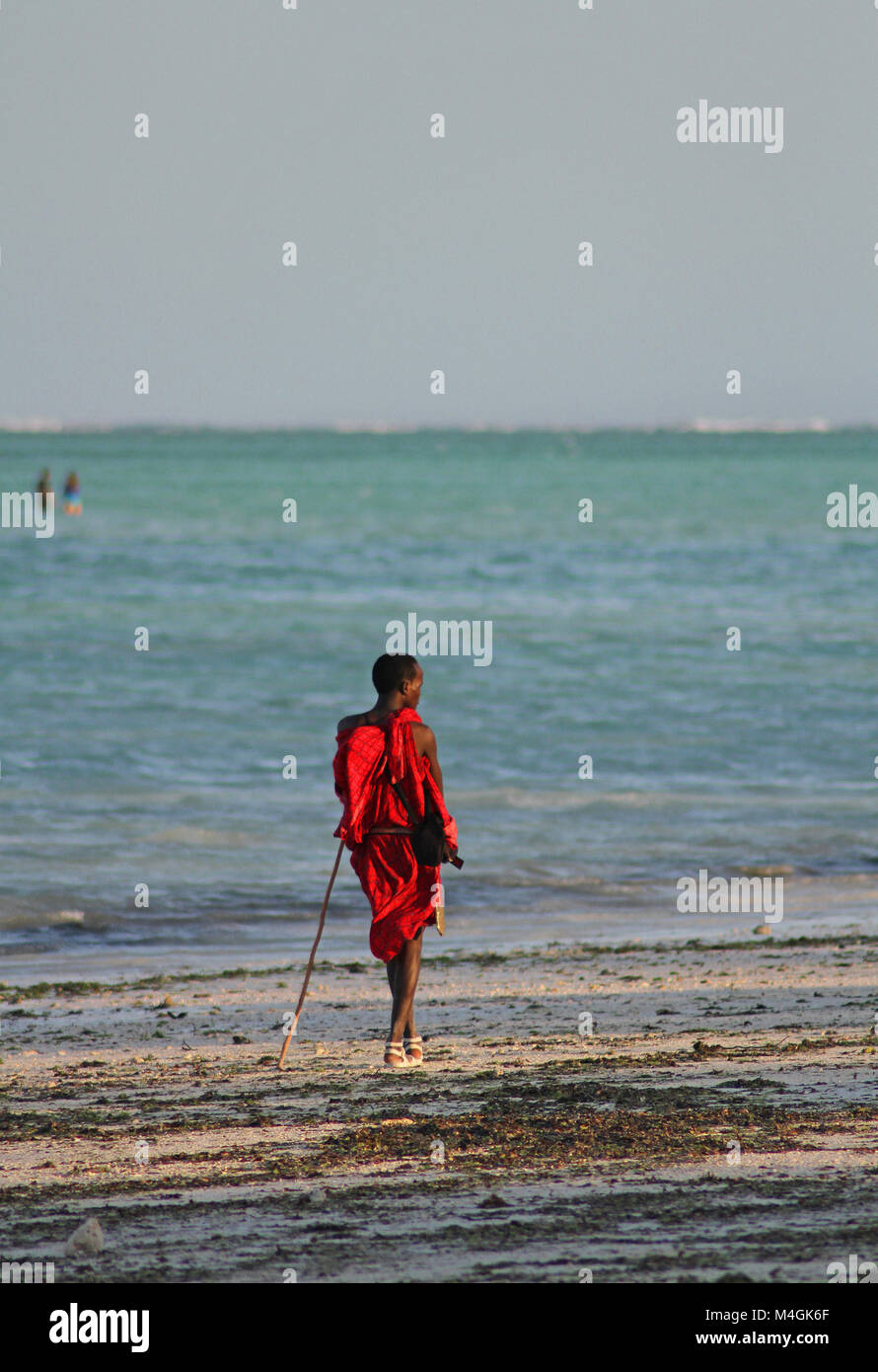 Homme massaï debout sur la plage au coucher du soleil, plage de Nungwi, Zanzibar, Tanzanie Banque D'Images