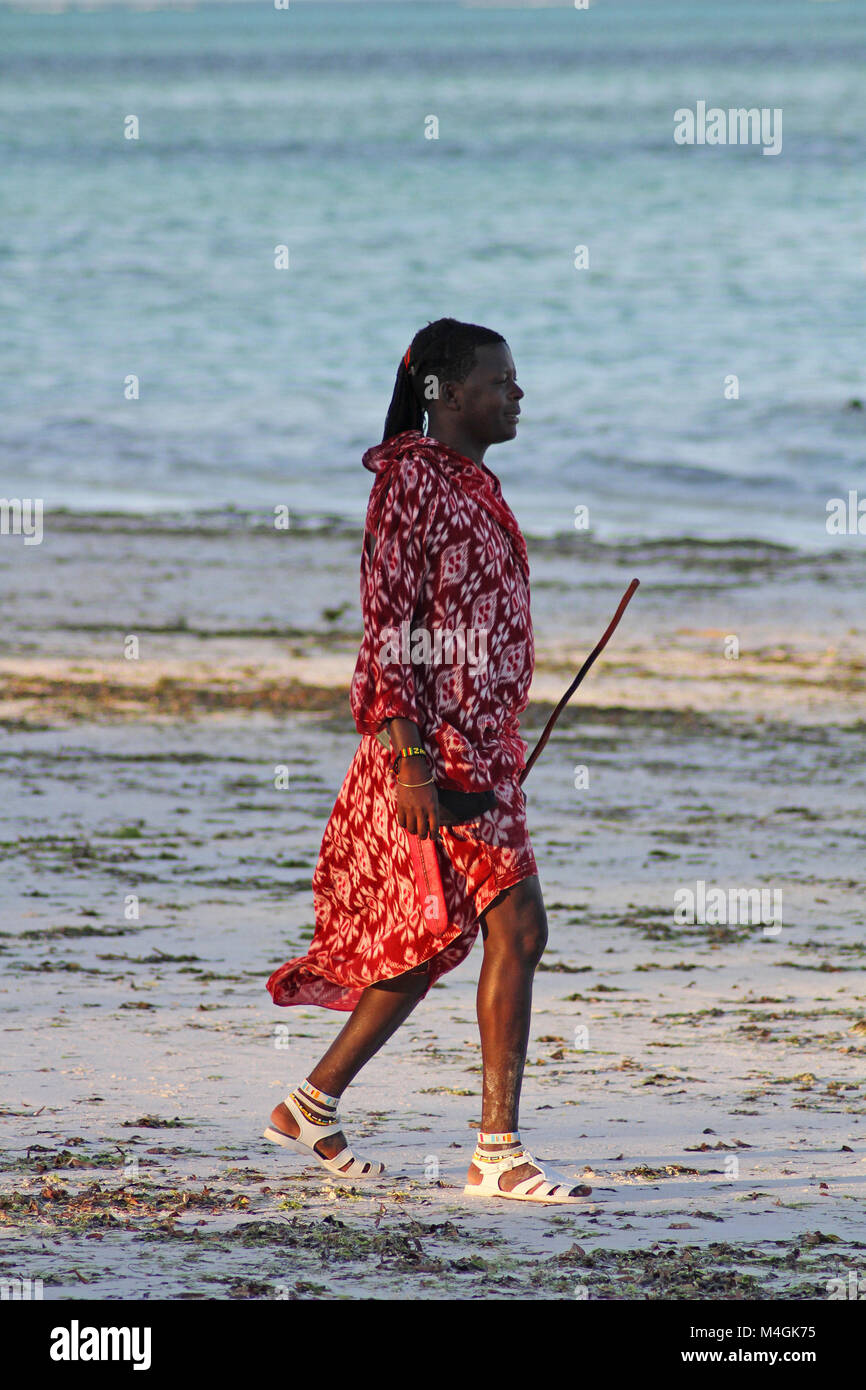 Homme massaï la marche sur la plage au coucher du soleil, plage de Nungwi, Zanzibar, Tanzanie Banque D'Images Homme massaï la marche sur la plage au coucher du soleil, plage de Nungwi, Zanzibar, Tanzanie Banque D'Images