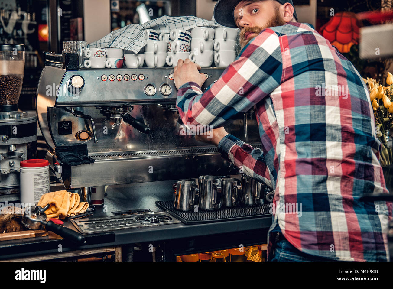 Homme barbu est faire le café dans une machine à café professionnelle ...